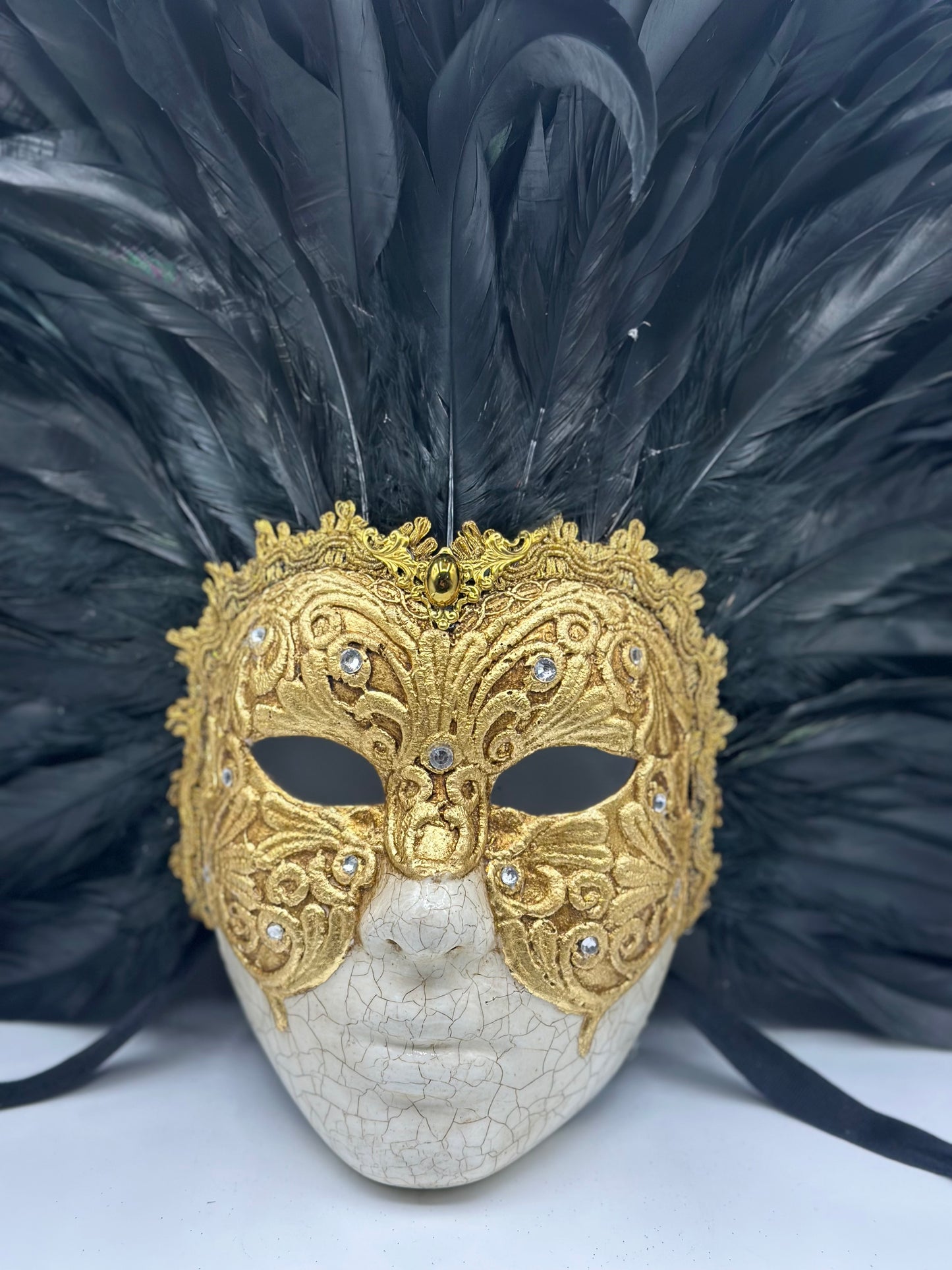 Full-face golden Venetian mask with black feathers
